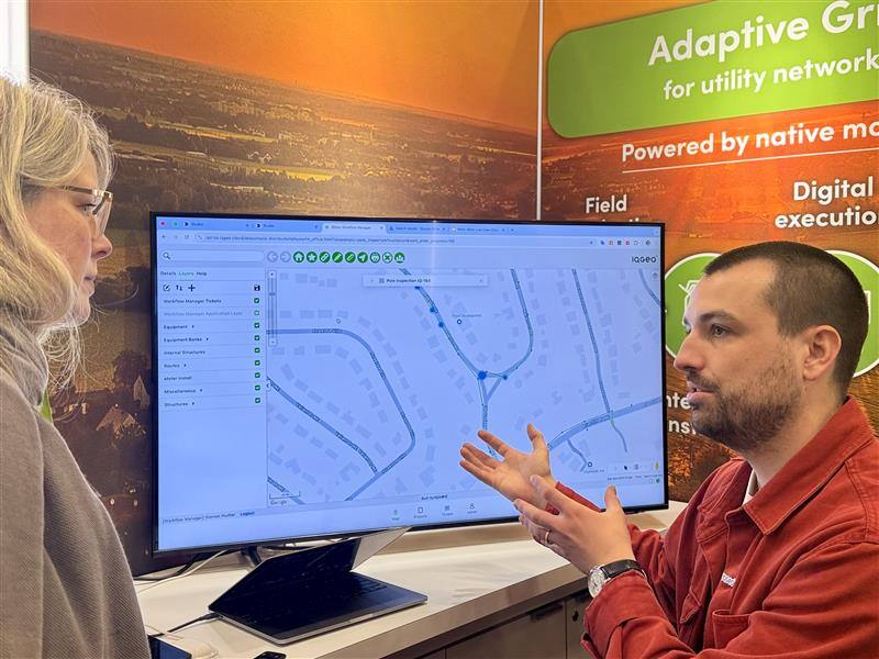 Close up booth picture from DISTRIBUTECH 2025 with the IQGeo software on screen