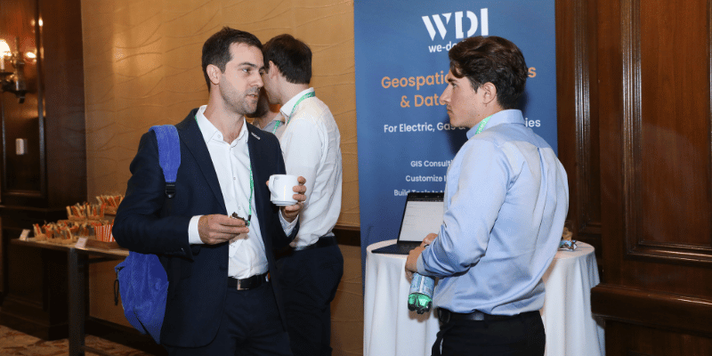 Attendees networking at the IQGeo Americas Meetup 2025 near the We Do IT partner pod