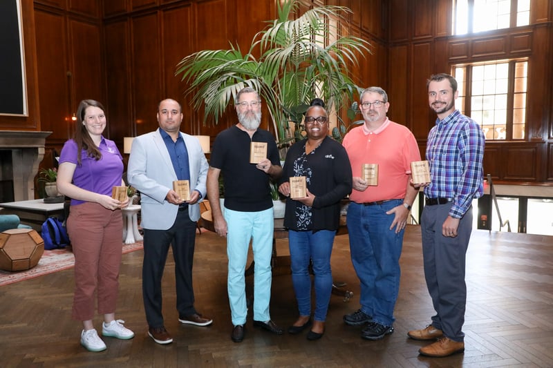 Group of six people holding wooden award plaques at the IQGeo Americas Meetup 2025, celebrating customer and partner innovation winners.